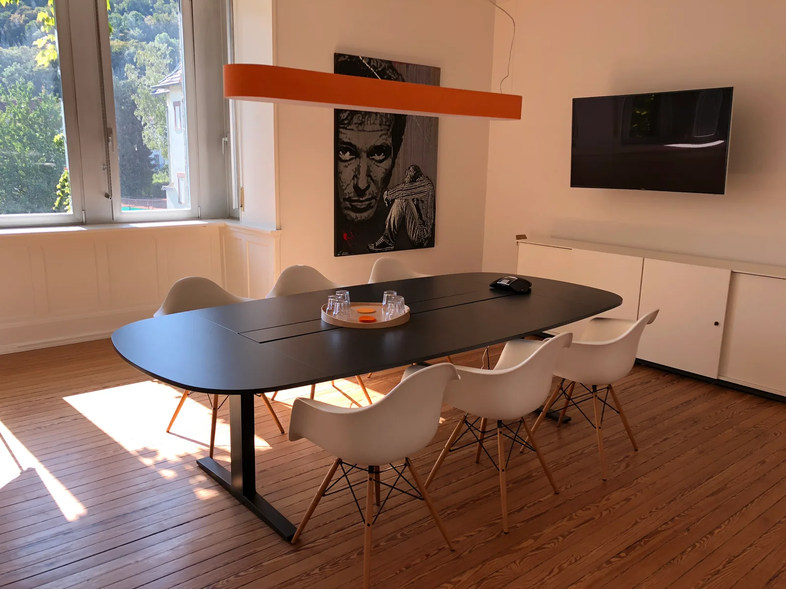 Meetingraum von Oyster Consulting mit großem Besprechungstisch und orangefarbener Leuchte